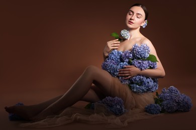 Photo of Beautiful young woman with hortensia flowers on brown background