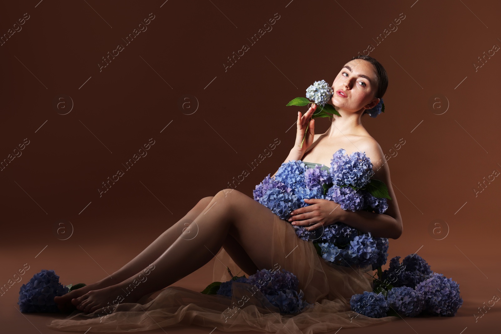 Beautiful young woman with hortensia flowers on brown background Photo of Beautiful young woman with hortensia flowers on brown background