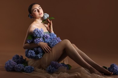 Photo of Beautiful young woman with hortensia flowers on brown background