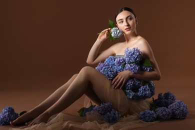 Photo of Beautiful young woman with hortensia flowers on brown background