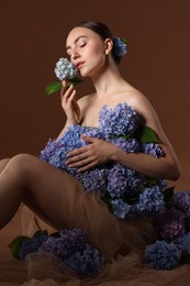 Photo of Beautiful young woman with hortensia flowers on brown background