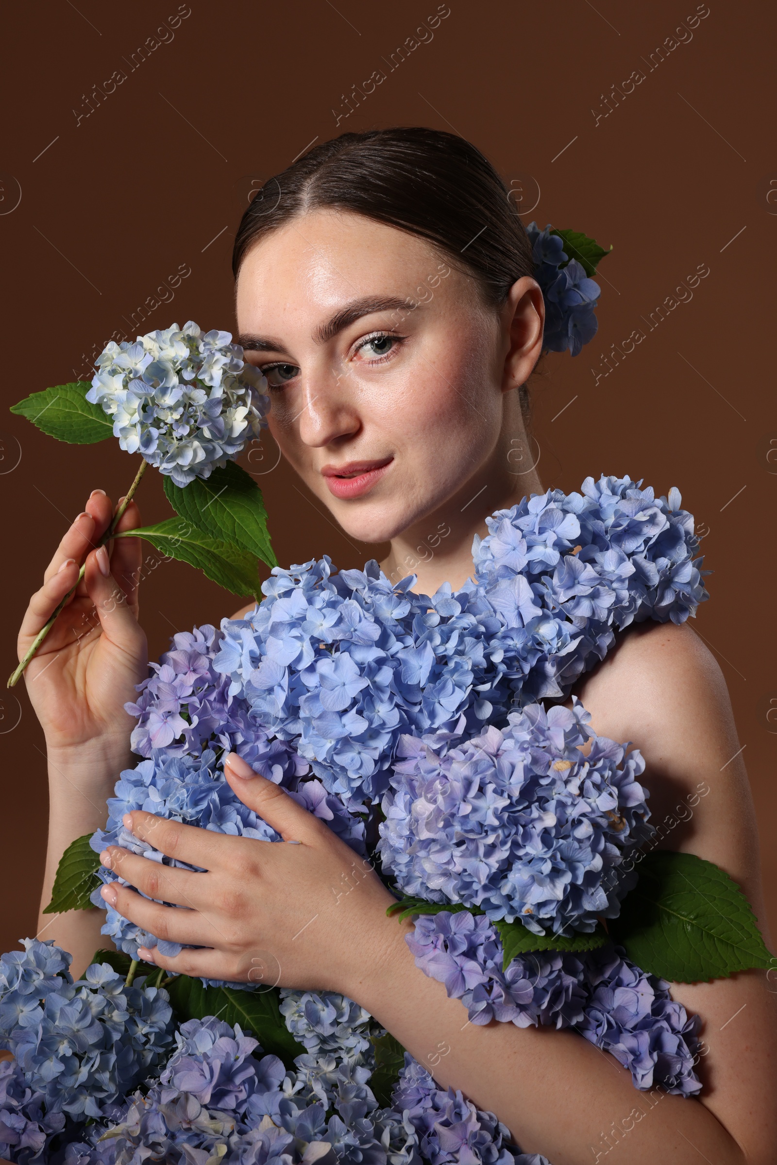 Photo of Beautiful young woman with hortensia flowers on brown background