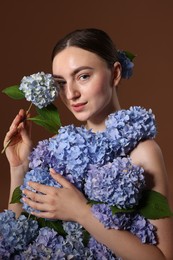 Photo of Beautiful young woman with hortensia flowers on brown background