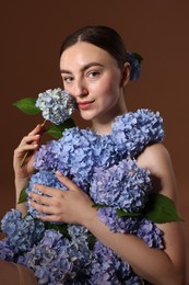 Photo of Beautiful young woman with hortensia flowers on brown background