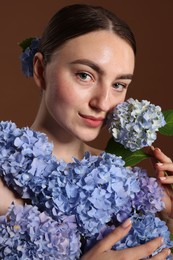 Photo of Beautiful young woman with hortensia flowers on brown background