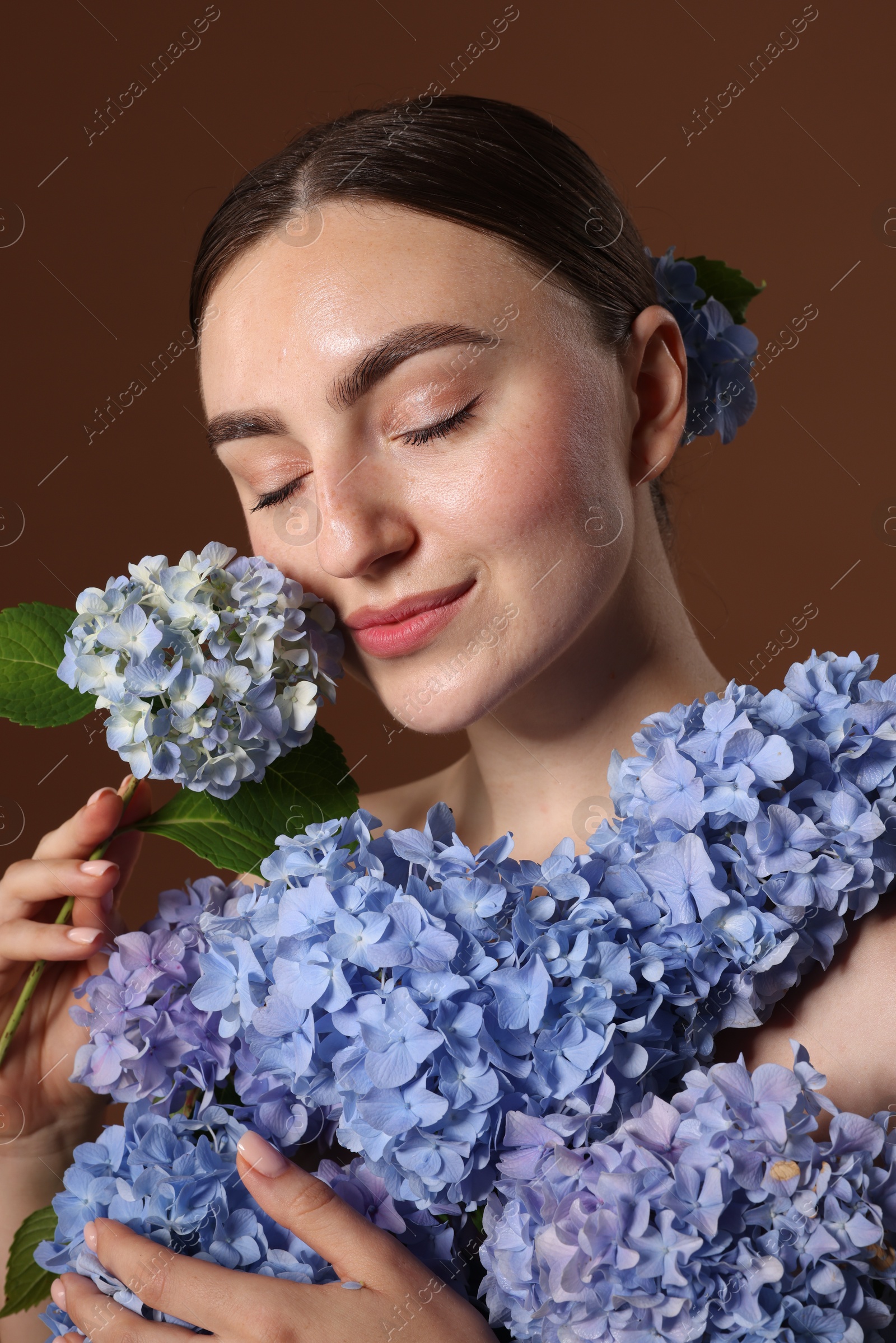 Beautiful young woman with hortensia flowers on brown background Photo of Beautiful young woman with hortensia flowers on brown background