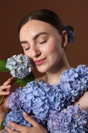 Photo of Beautiful young woman with hortensia flowers on brown background