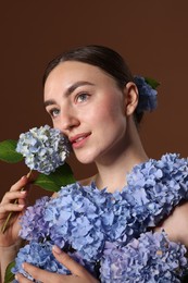 Photo of Beautiful young woman with hortensia flowers on brown background