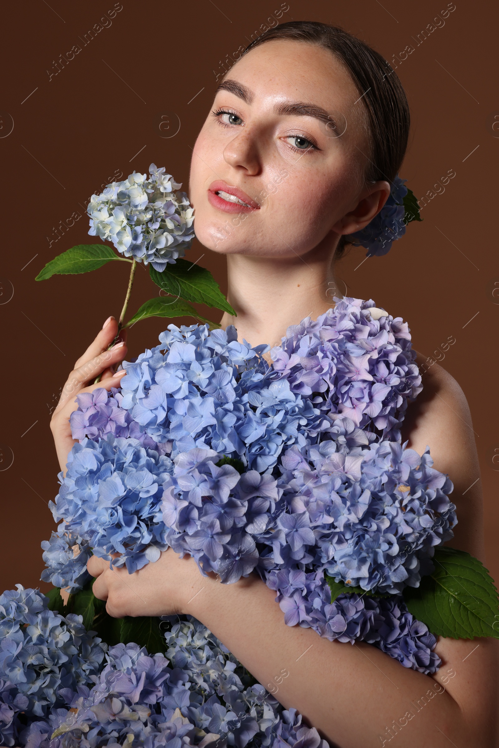 Beautiful young woman with hortensia flowers on brown background Photo of Beautiful young woman with hortensia flowers on brown background