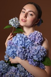 Photo of Beautiful young woman with hortensia flowers on brown background