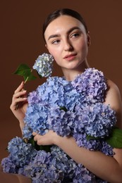Photo of Beautiful young woman with hortensia flowers on brown background