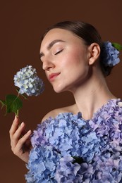 Photo of Beautiful young woman with hortensia flowers on brown background