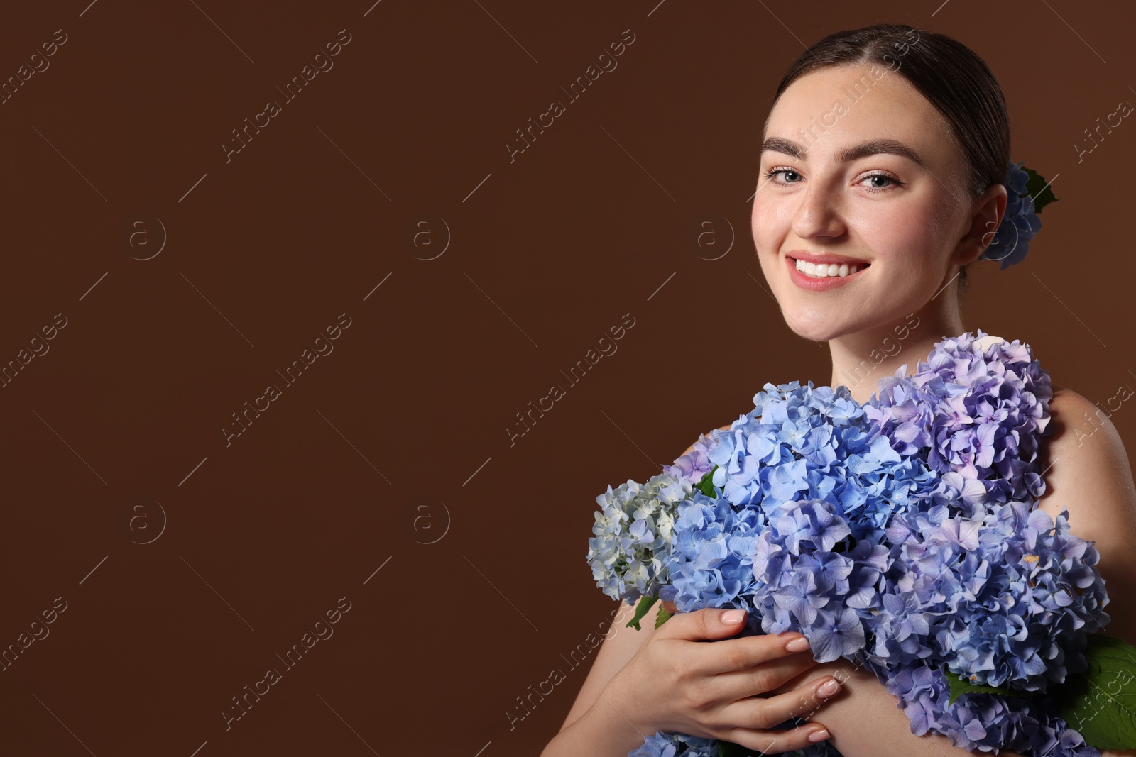 Photo of Beautiful young woman with hortensia flowers on brown background. Space for text