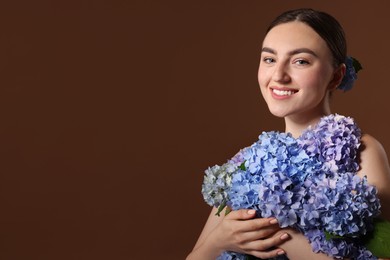 Photo of Beautiful young woman with hortensia flowers on brown background. Space for text
