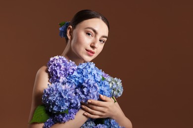 Photo of Beautiful young woman with hortensia flowers on brown background. Space for text