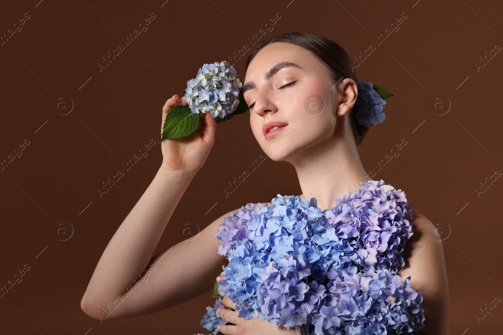 Photo of Beautiful young woman with hortensia flowers on brown background