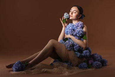 Photo of Beautiful young woman with hortensia flowers on brown background