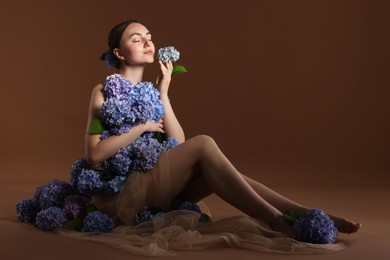 Photo of Beautiful young woman with hortensia flowers on brown background