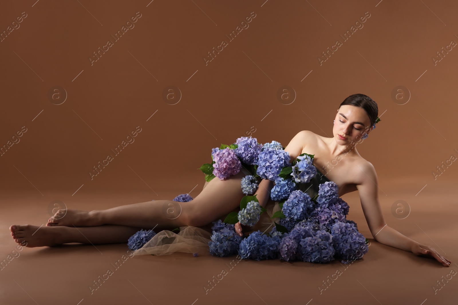 Photo of Beautiful young woman with hortensia flowers on brown background