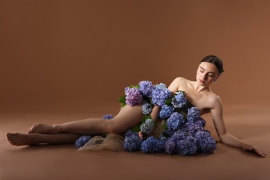 Photo of Beautiful young woman with hortensia flowers on brown background