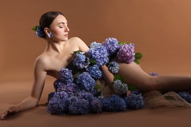 Photo of Beautiful young woman with hortensia flowers on brown background