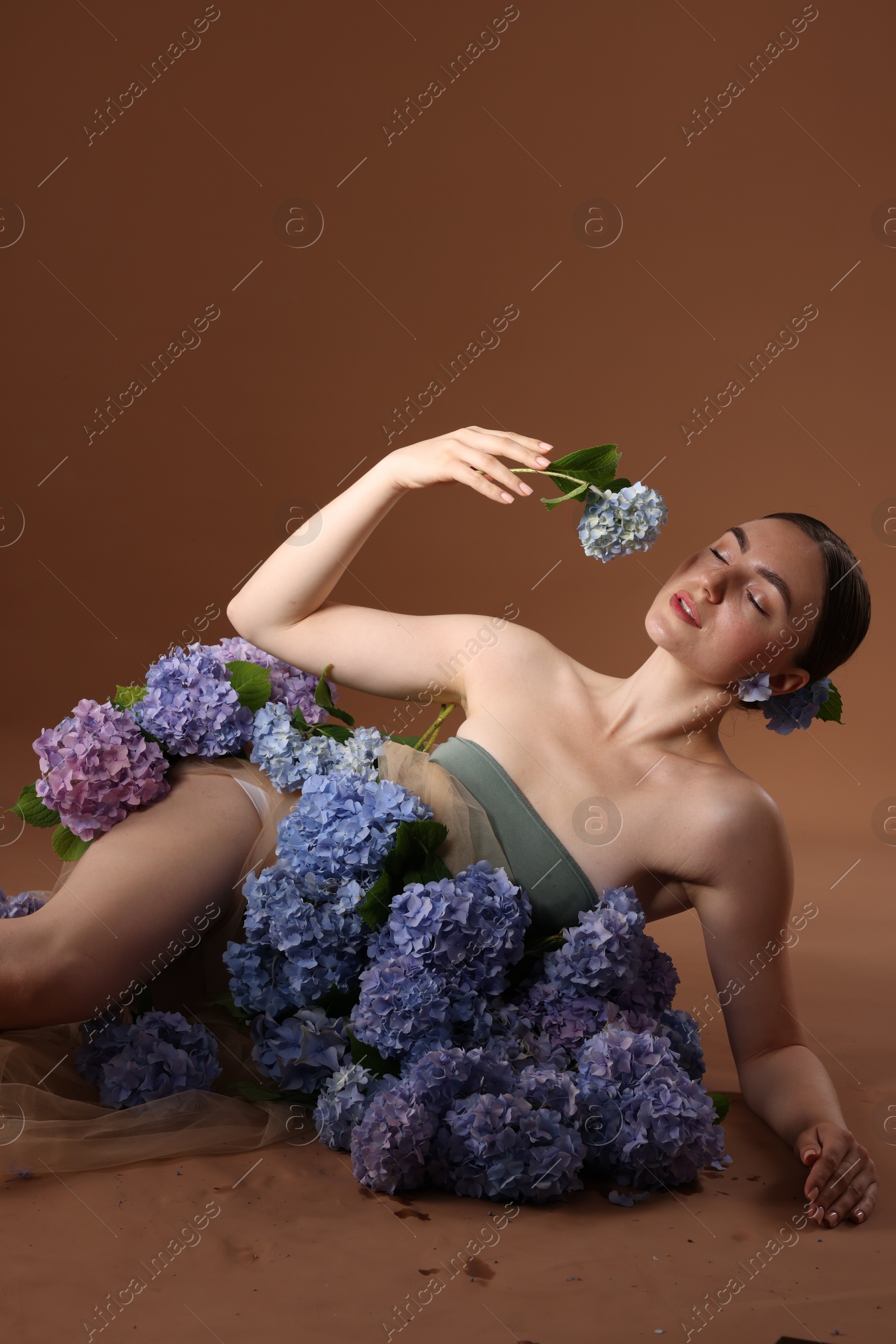 Photo of Beautiful young woman with hortensia flowers on brown background