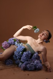 Photo of Beautiful young woman with hortensia flowers on brown background