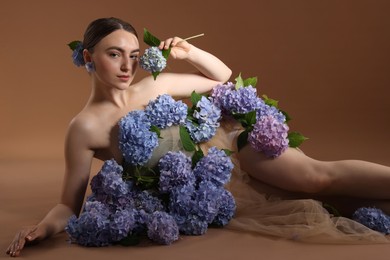 Photo of Beautiful young woman with hortensia flowers on brown background