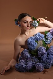 Photo of Beautiful young woman with hortensia flowers on brown background