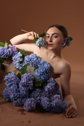Photo of Beautiful young woman with hortensia flowers on brown background