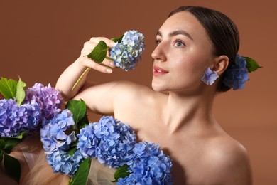 Photo of Beautiful young woman with hortensia flowers on brown background