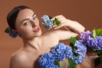 Photo of Beautiful young woman with hortensia flowers on brown background