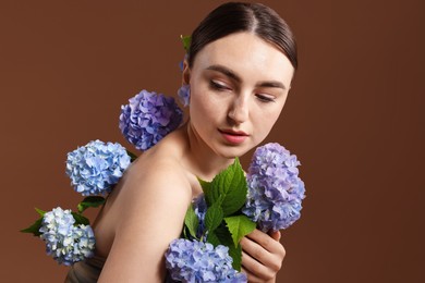 Photo of Beautiful young woman with hortensia flowers on brown background