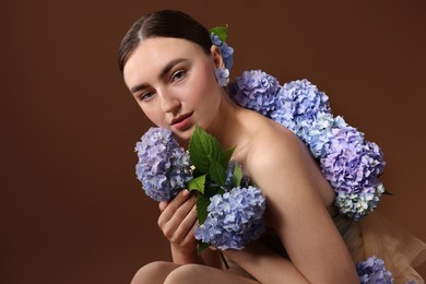 Photo of Beautiful young woman with hortensia flowers on brown background