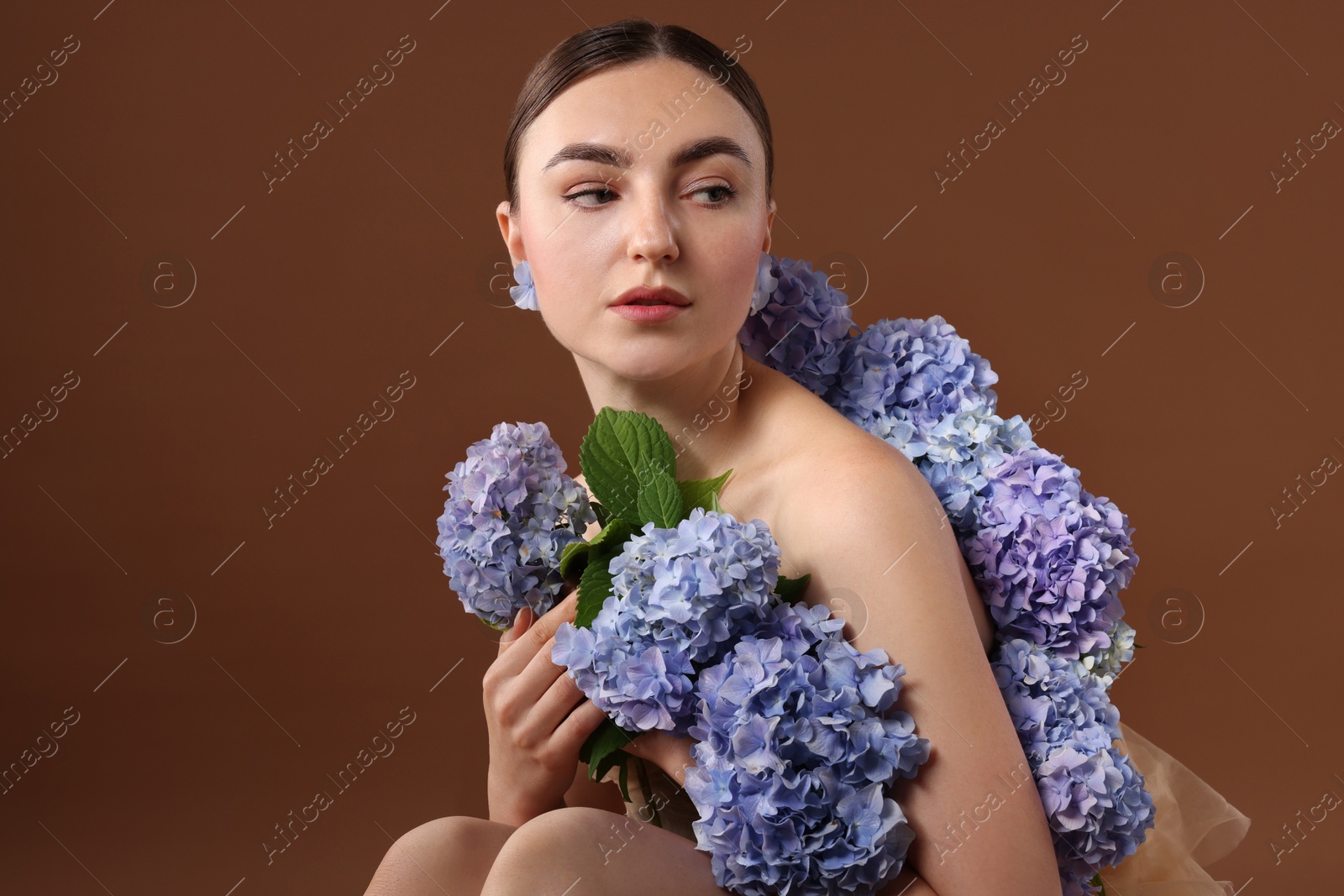 Photo of Beautiful young woman with hortensia flowers on brown background