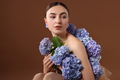 Photo of Beautiful young woman with hortensia flowers on brown background