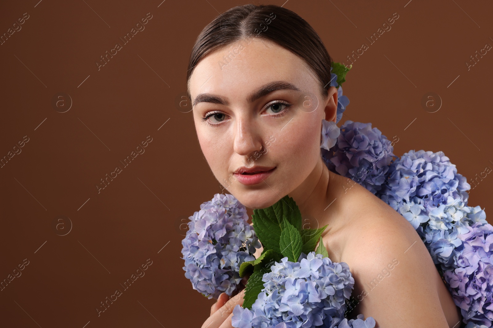 Photo of Beautiful young woman with hortensia flowers on brown background. Space for text