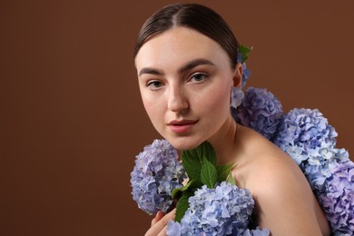 Photo of Beautiful young woman with hortensia flowers on brown background. Space for text