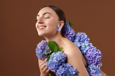 Photo of Beautiful young woman with hortensia flowers on brown background