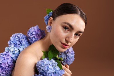 Photo of Beautiful young woman with hortensia flowers on brown background