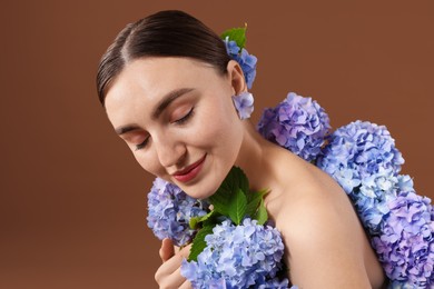 Photo of Beautiful young woman with hortensia flowers on brown background