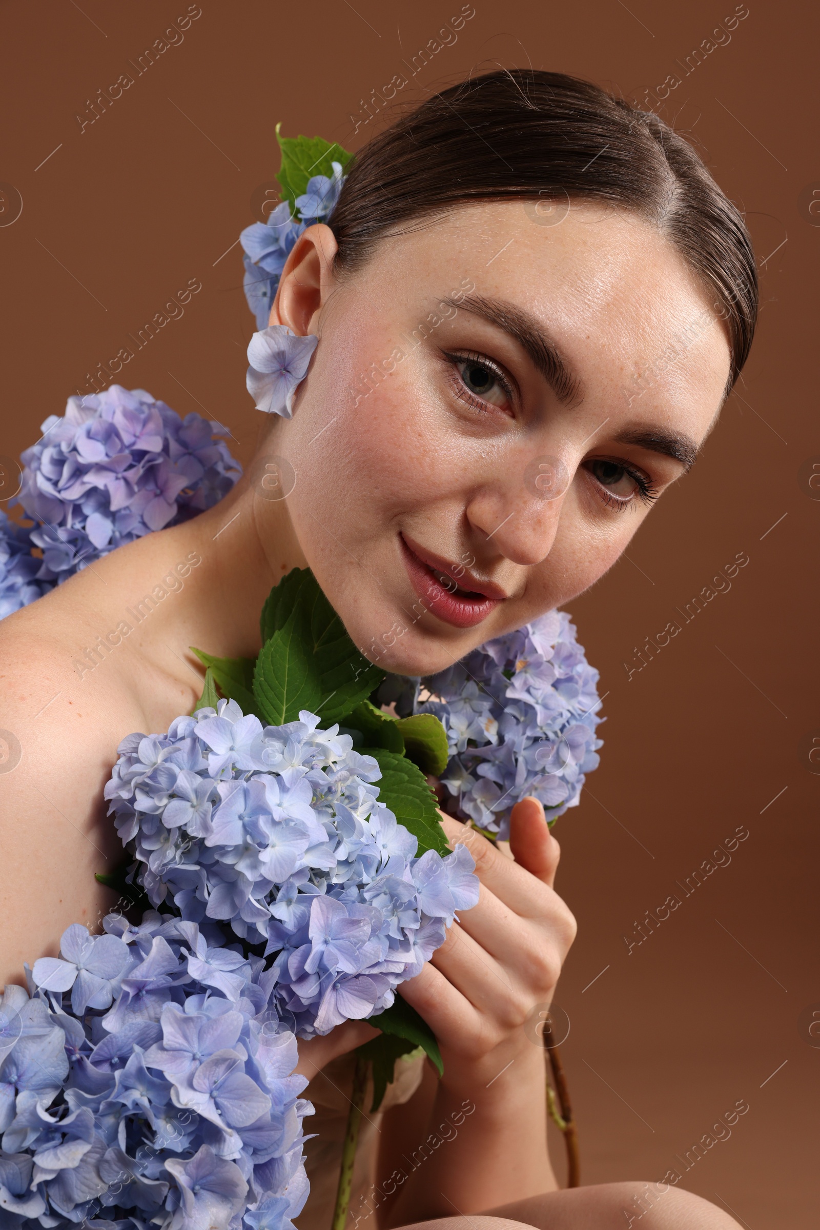 Photo of Beautiful young woman with hortensia flowers on brown background