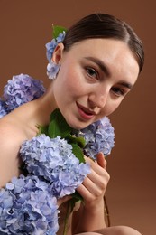 Photo of Beautiful young woman with hortensia flowers on brown background