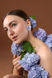 Photo of Beautiful young woman with hortensia flowers on brown background