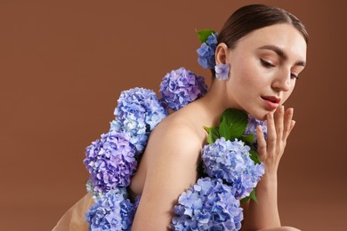 Photo of Beautiful young woman with hortensia flowers on brown background