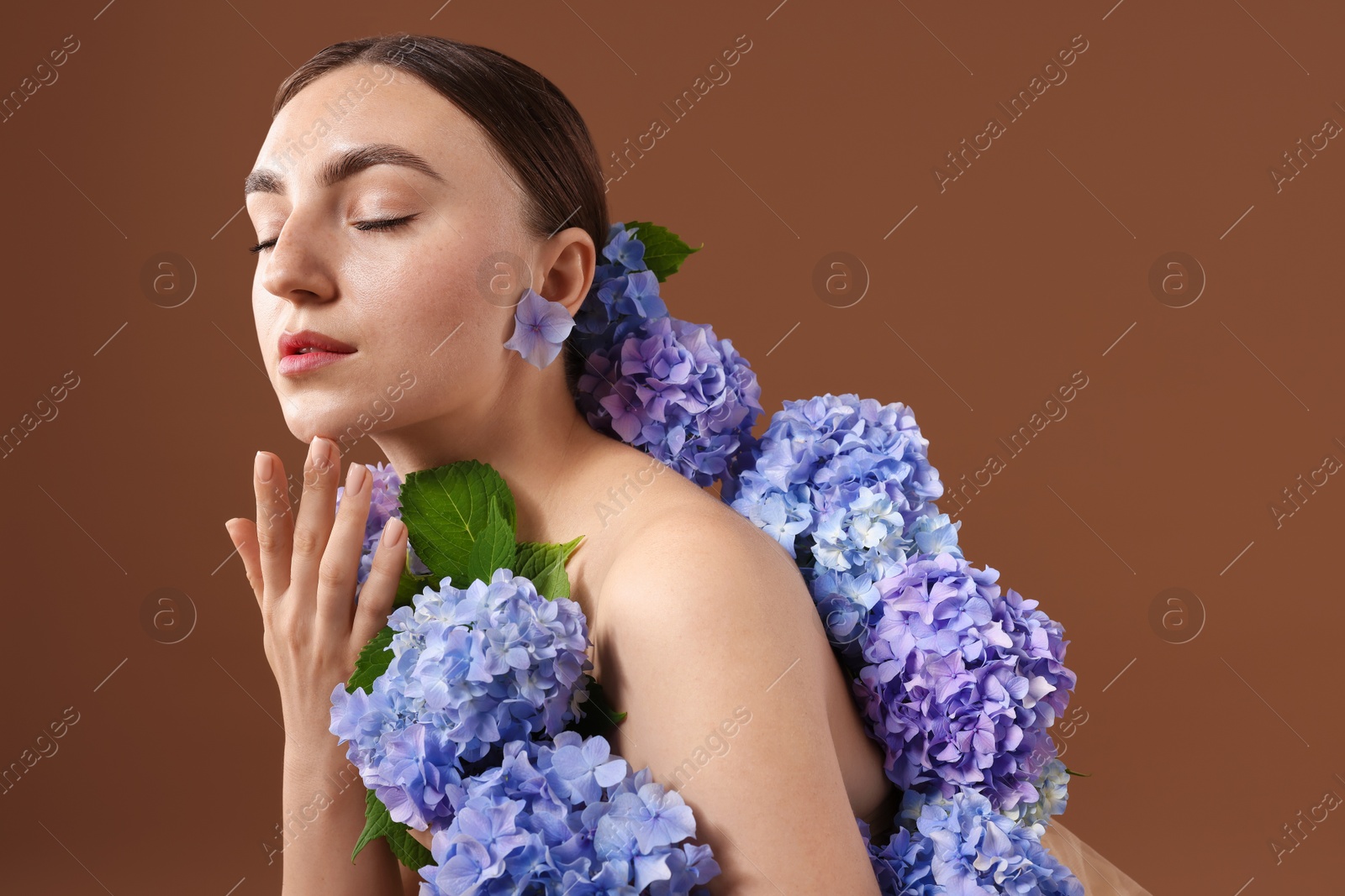 Photo of Beautiful young woman with hortensia flowers on brown background