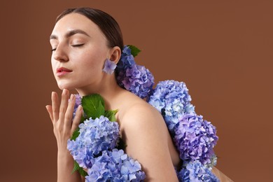 Photo of Beautiful young woman with hortensia flowers on brown background