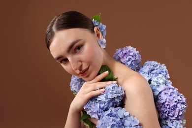 Photo of Beautiful young woman with hortensia flowers on brown background