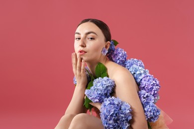 Photo of Beautiful young woman with hortensia flowers on color background