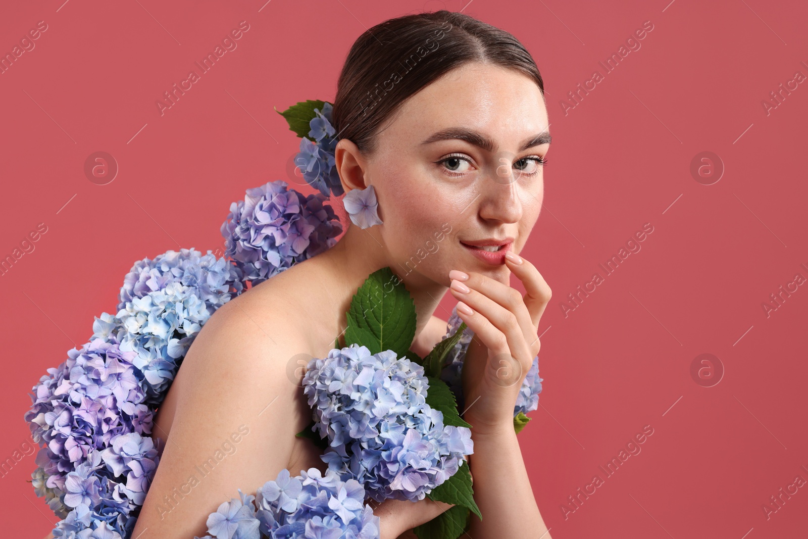 Photo of Beautiful young woman with hortensia flowers on color background